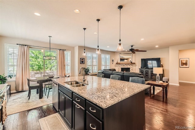 kitchen with recessed lighting, a sink, a lit fireplace, stainless steel dishwasher, and dark wood-style floors