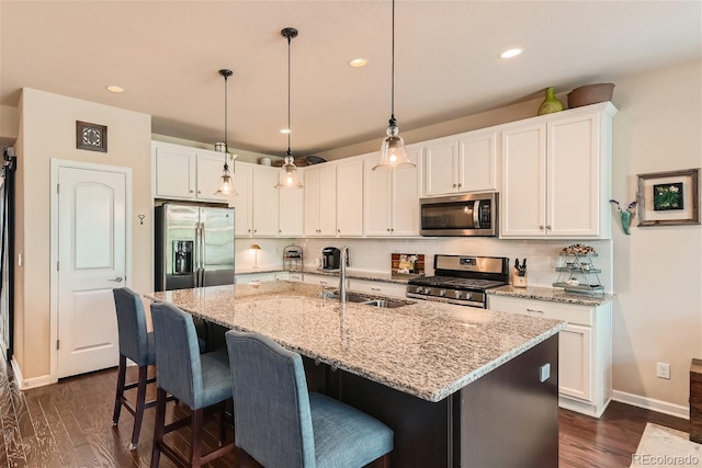 kitchen with stainless steel appliances, dark wood-type flooring, a sink, white cabinets, and decorative backsplash