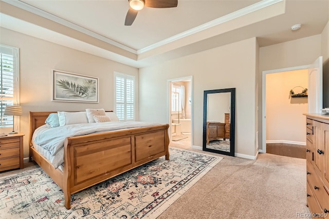 bedroom featuring light carpet, baseboards, a raised ceiling, ornamental molding, and ensuite bathroom