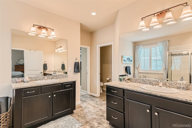 full bath with toilet, a stall shower, two vanities, and a sink