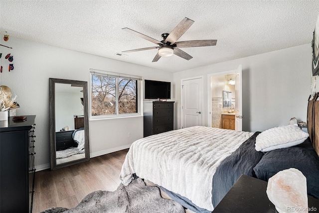 bedroom featuring a ceiling fan, baseboards, wood finished floors, visible vents, and a textured ceiling