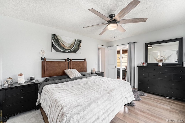 bedroom featuring visible vents, light wood-style flooring, a textured ceiling, and ceiling fan