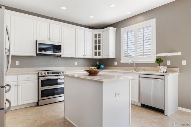 10978 Ashurst Ln, Highlands Ranch, CO 80130 - kitchen featuring stainless steel appliances, white cabinets, light countertops, a center island, and light tile patterned floors