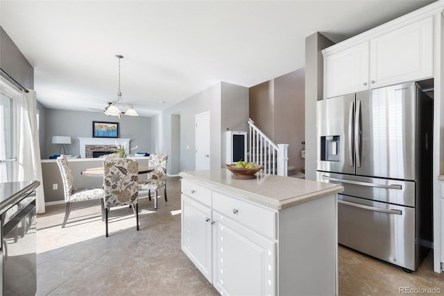 10978 Ashurst Ln, Highlands Ranch, CO 80130 - kitchen with stainless steel appliances, a fireplace, white cabinetry, light countertops, and hanging light fixtures