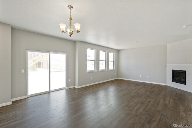 14249 Beebalm Ave, Parker, CO 80134 - unfurnished living room featuring a chandelier, dark wood-style floors, a tile fireplace, and baseboards