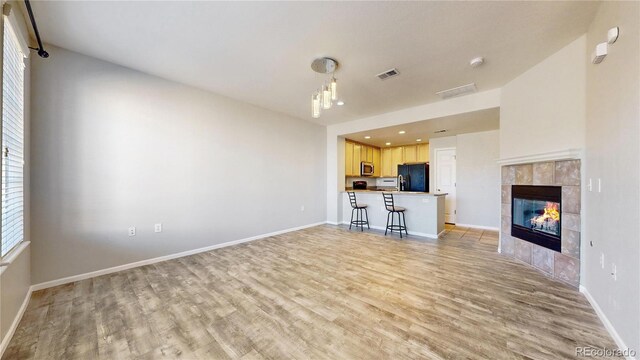 16047 E Geddes Ln Unit 128, Aurora, CO 80016 - unfurnished living room featuring light wood finished floors, baseboards, a tile fireplace, and recessed lighting