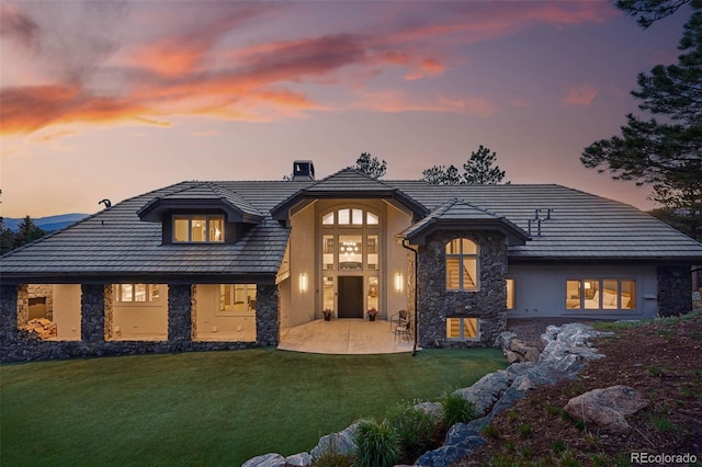 2548 Keystone Dr, Evergreen, CO 80439 - view of front of house featuring stone siding, a chimney, a lawn, stucco siding, and a patio area