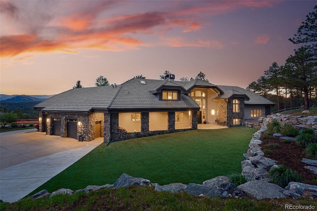 2548 Keystone Dr, Evergreen, CO 80439 - view of front facade featuring stone siding, a lawn, driveway, a tile roof, and an attached garage