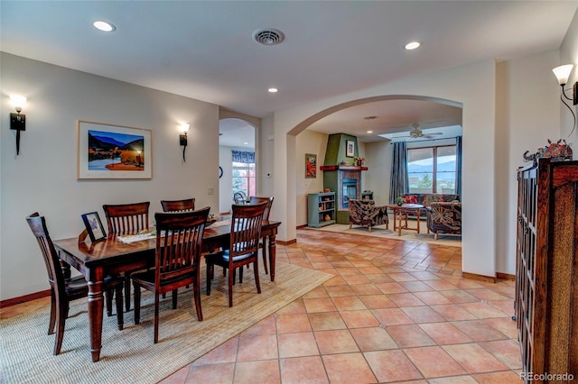 dining space featuring light tile patterned floors, a fireplace, and ceiling fan