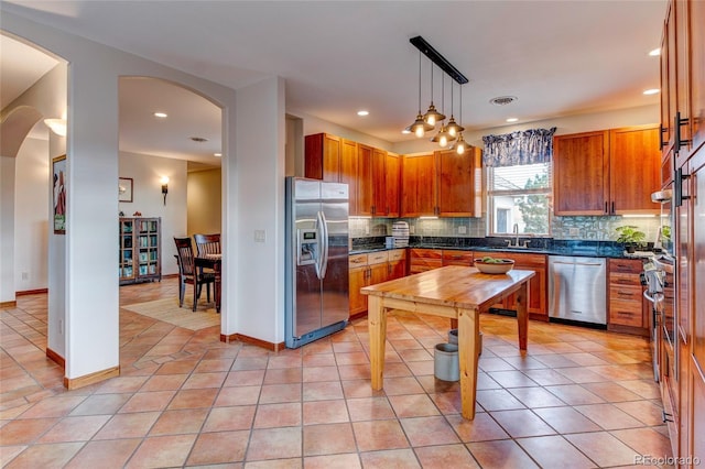 kitchen featuring decorative backsplash, sink, decorative light fixtures, light tile patterned floors, and appliances with stainless steel finishes