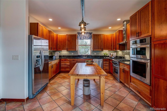 kitchen featuring wall chimney range hood, appliances with stainless steel finishes, decorative light fixtures, and decorative backsplash