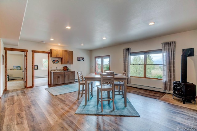 dining area featuring a baseboard heating unit, light wood-type flooring, and a wood stove