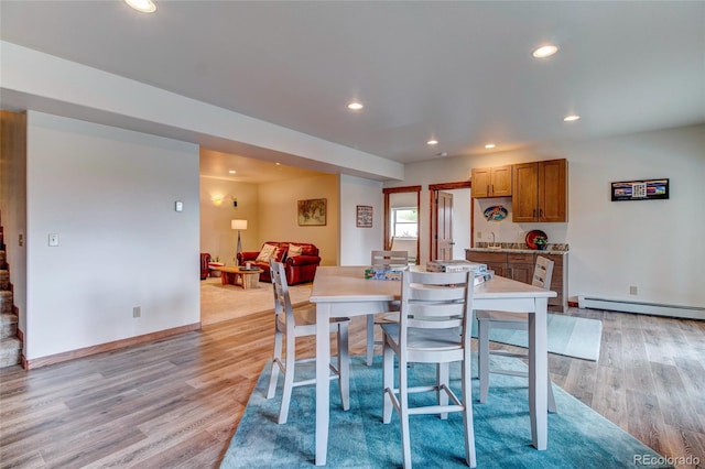 dining area with light hardwood / wood-style floors, baseboard heating, and sink