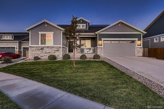 craftsman-style house featuring a lawn, covered porch, and a garage