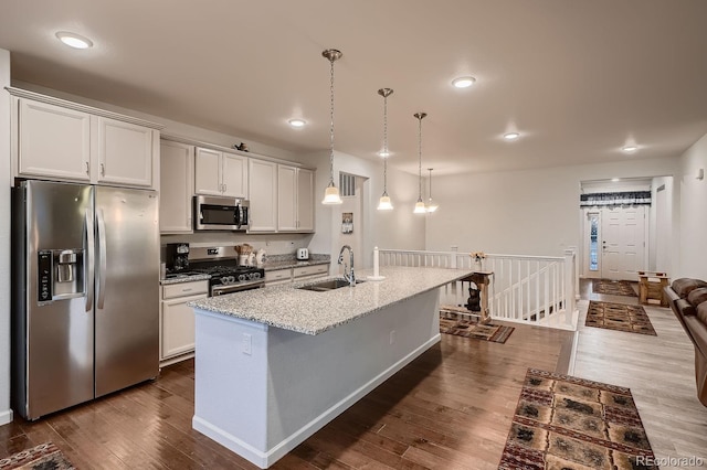 kitchen featuring white cabinets, pendant lighting, a center island with sink, appliances with stainless steel finishes, and dark hardwood / wood-style flooring