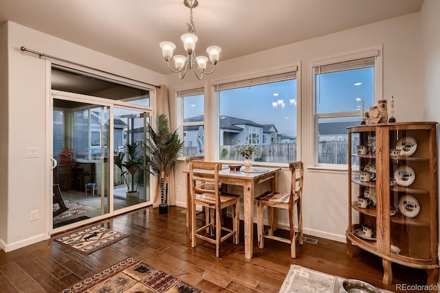 dining space with a notable chandelier, a healthy amount of sunlight, and dark hardwood / wood-style flooring