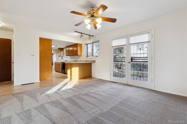 unfurnished living room with ceiling fan, track lighting, and light carpet