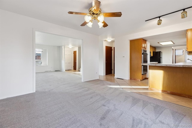 unfurnished living room featuring ceiling fan, track lighting, and light carpet