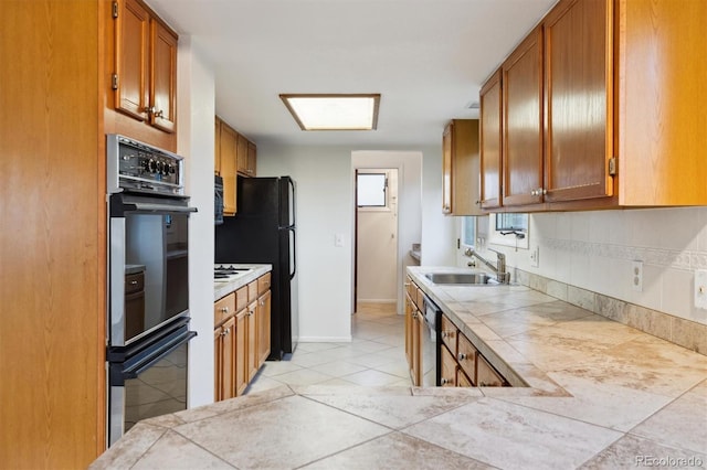 kitchen featuring dishwasher, sink, tile counters, and stainless steel double oven