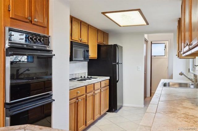 kitchen with sink, tile counters, black appliances, and light tile patterned flooring