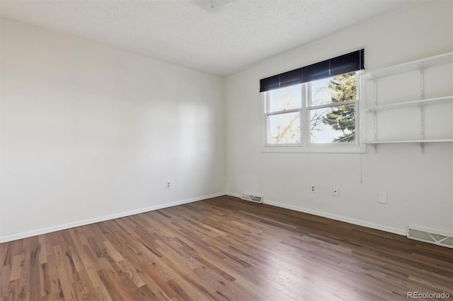 empty room featuring wood-type flooring and a textured ceiling