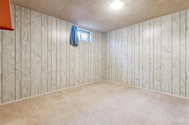 carpeted empty room with a textured ceiling and wood walls