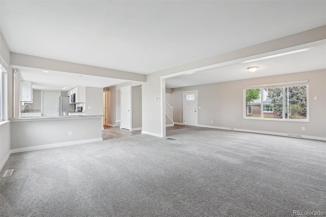 4623 S Kalispell Way, Aurora, CO 80015 - unfurnished living room featuring light carpet, baseboards, and stairway