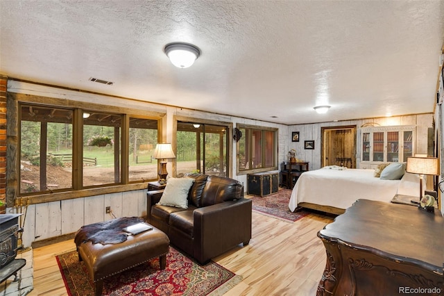 89 Aspen Leaf Ln, Bellvue, CO 80512 - bedroom featuring light wood-style flooring, a textured ceiling, a wood stove, and wood walls