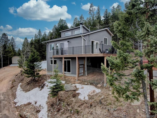 back of house with a deck and an outbuilding