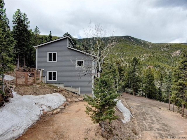 view of side of property with a forest view and a mountain view