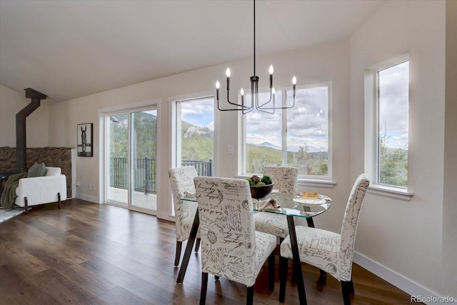 dining area with baseboards, dark wood-style floors, a healthy amount of sunlight, and a notable chandelier