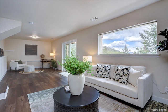 living room featuring baseboards, visible vents, and wood finished floors