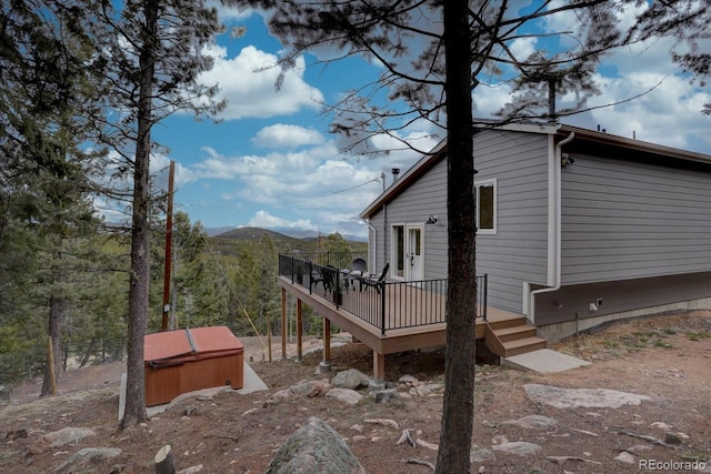 view of home's exterior with a deck with mountain view and a hot tub