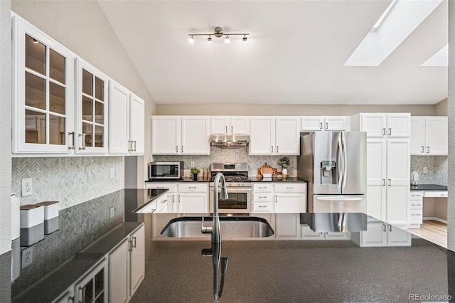 6713 W 98th Cir, Westminster, CO 80021 - kitchen with appliances with stainless steel finishes, under cabinet range hood, dark countertops, backsplash, and lofted ceiling