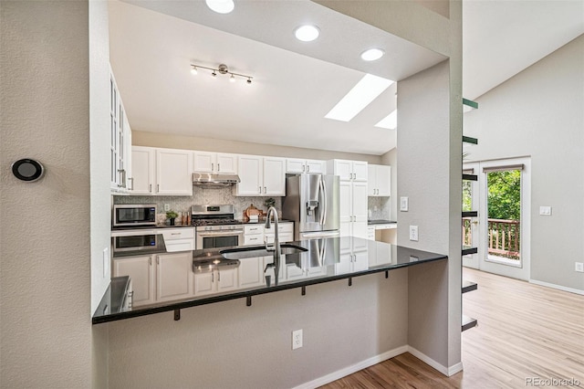 6713 W 98th Cir, Westminster, CO 80021 - kitchen featuring appliances with stainless steel finishes, a skylight, dark countertops, decorative backsplash, and light wood finished floors