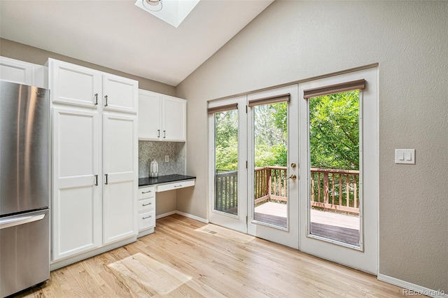 6713 W 98th Cir, Westminster, CO 80021 - kitchen with freestanding refrigerator, light wood-type flooring, vaulted ceiling, built in desk, and white cabinets