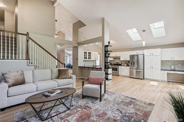 6713 W 98th Cir, Westminster, CO 80021 - living area with high vaulted ceiling, light wood-type flooring, a skylight, and stairs