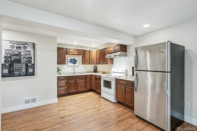 6713 W 98th Cir, Westminster, CO 80021 - kitchen with freestanding refrigerator, white range with electric cooktop, under cabinet range hood, light wood-type flooring, and light countertops