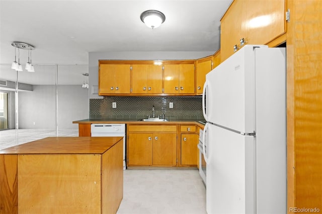 kitchen featuring brown cabinetry, white appliances, a sink, and decorative backsplash