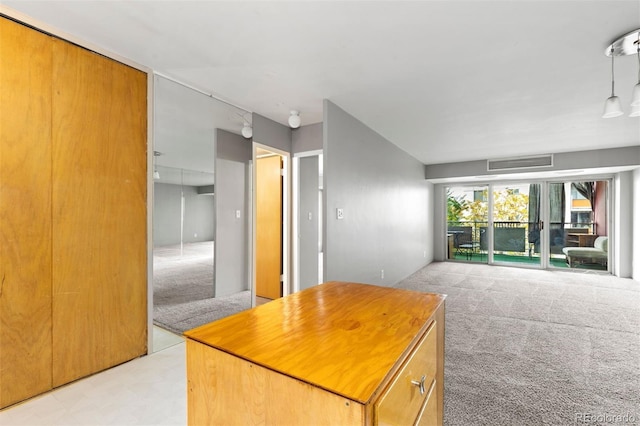 kitchen featuring light colored carpet, a kitchen island, visible vents, open floor plan, and hanging light fixtures