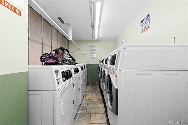 community laundry room with visible vents, washer and clothes dryer, and stone finish floor