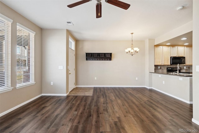 unfurnished living room featuring dark wood-style floors, visible vents, ceiling fan with notable chandelier, and baseboards