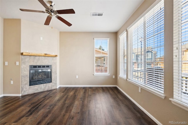 unfurnished living room with visible vents, wood finished floors, baseboards, ceiling fan, and a tile fireplace