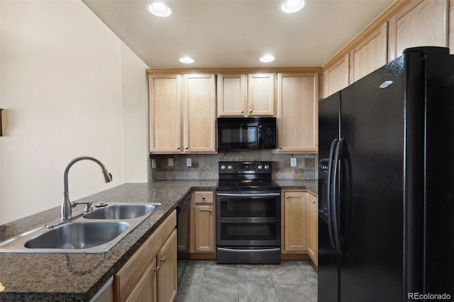 kitchen featuring light brown cabinetry, a peninsula, black appliances, and a sink