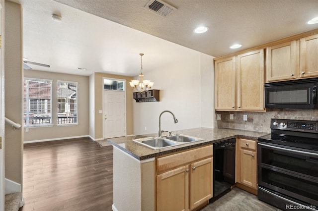 kitchen with black appliances, a peninsula, light brown cabinetry, and a sink