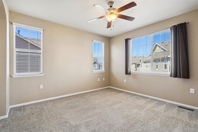 carpeted spare room featuring visible vents, baseboards, and a ceiling fan