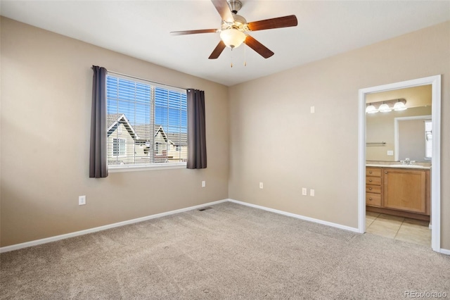 unfurnished bedroom with visible vents, baseboards, a sink, light colored carpet, and connected bathroom