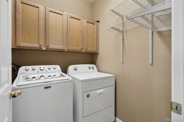 washroom featuring cabinet space and separate washer and dryer