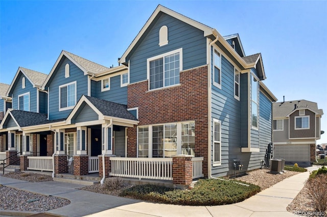 view of front of home with central air condition unit, covered porch, and brick siding