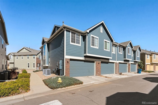 view of front of house with a residential view, central AC unit, and an attached garage